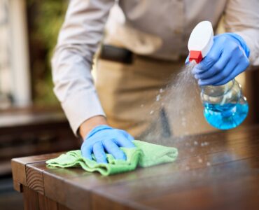 Close-up of waitress disinfecting tables at outdoor cafe.